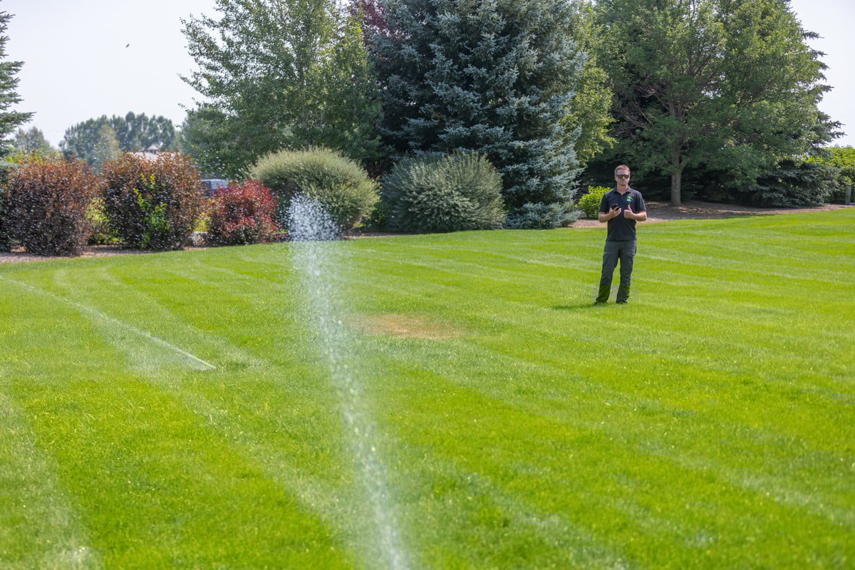 lawn care technician calibrating a sprinkler in an idaho falls lawn