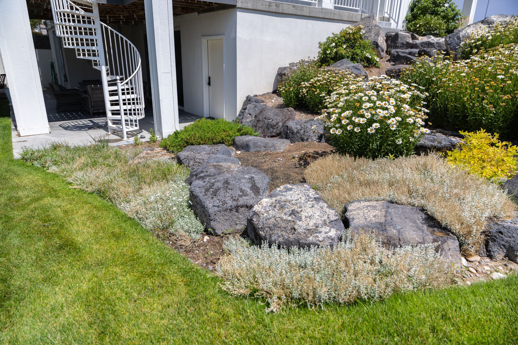 landscape maintenance homeowner backyard rock garden flower bed shrubs green grass yard