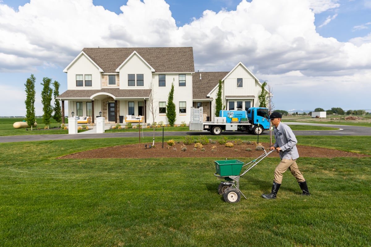 lawn care technician fertilizes lawn