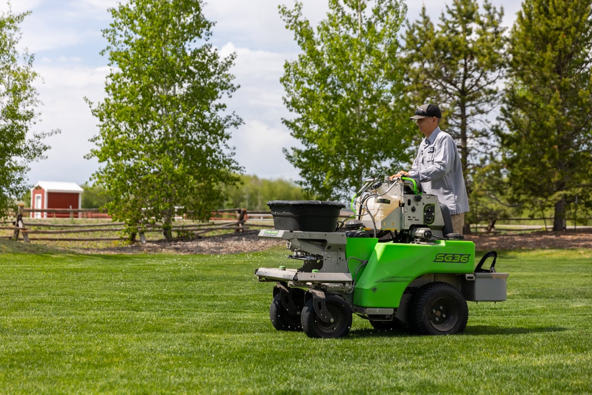 lawn care expert fertilizes grass