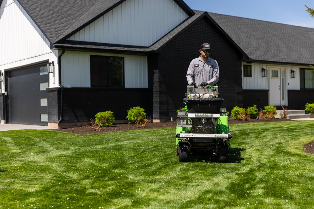 lawn care technician fertilizes grass