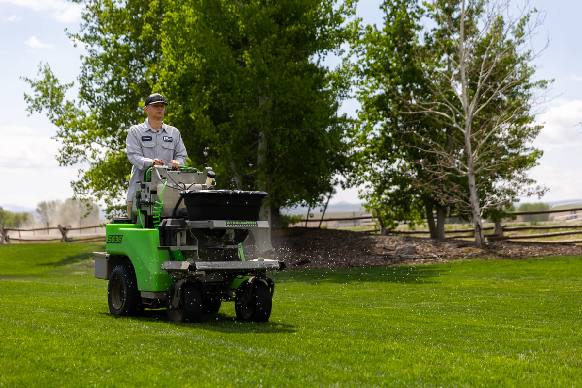 lawn care technician fertilizes grass