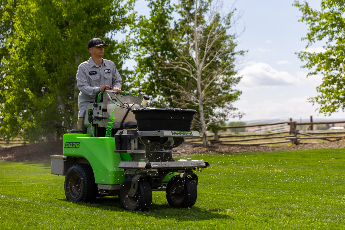 lawn care technician fertilizes grass