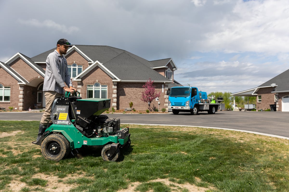 lawn care technician aerates grass