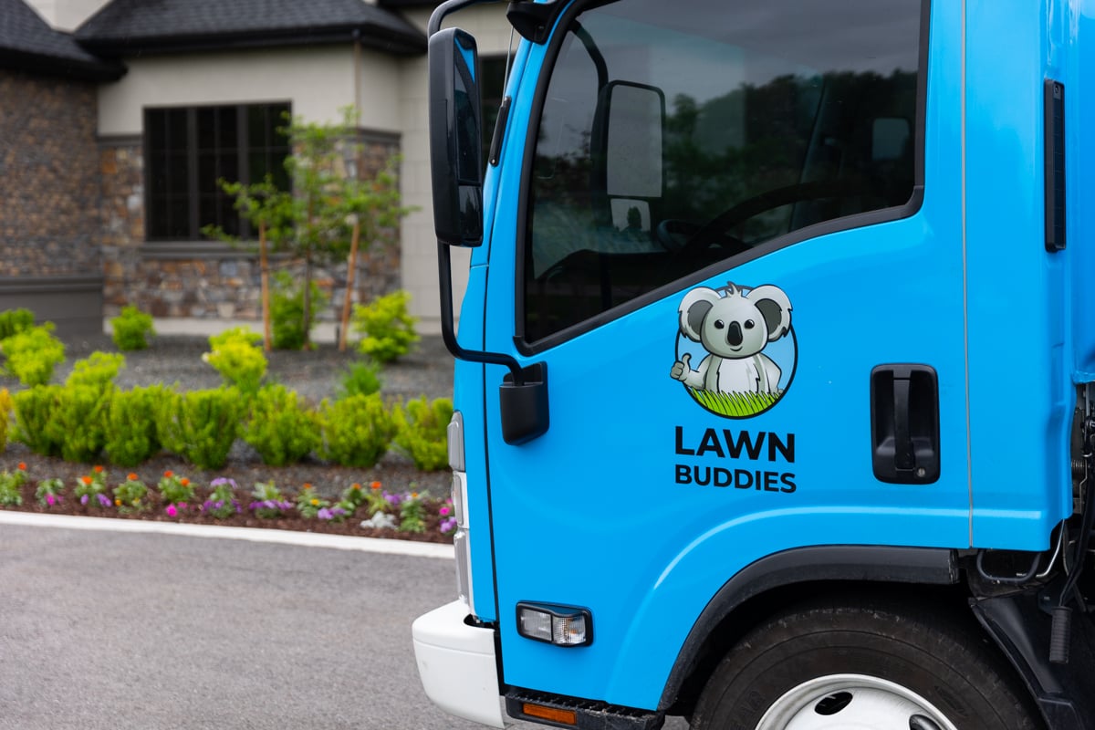 truck with lawn buddies logo parked in front of home