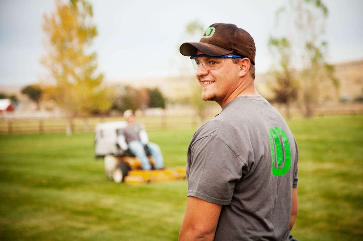 lawn care team mows lawn in backyard