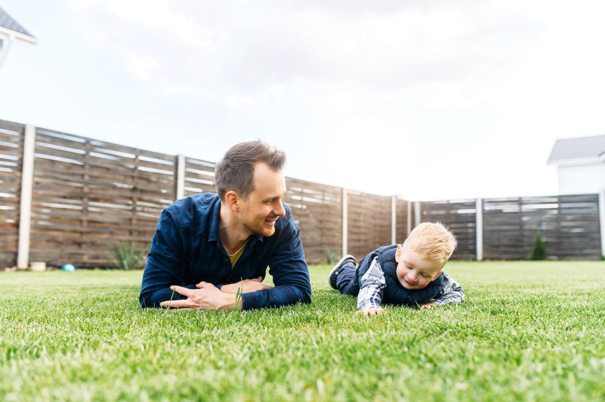 man and child lay in healthy green grass