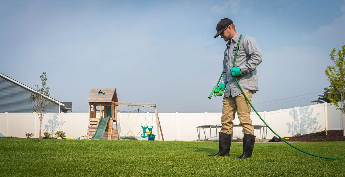 lawn care technician sprays for weeds