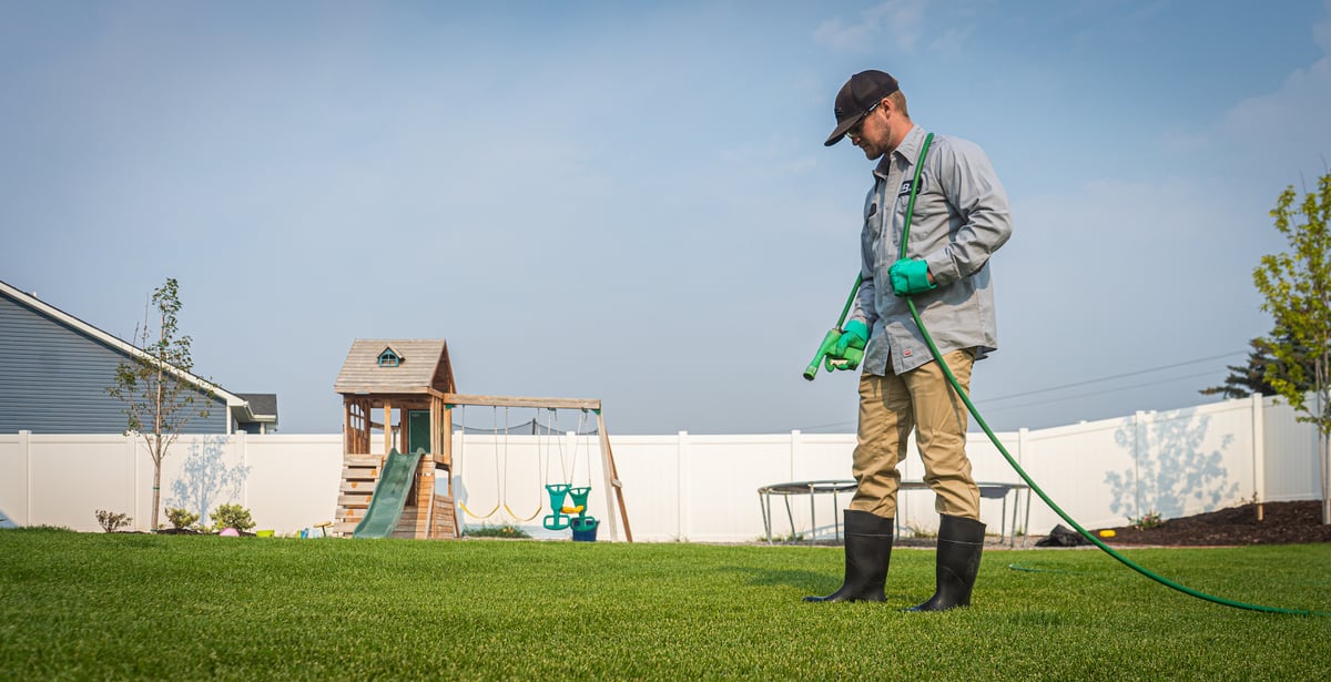 lawn technician sprays lawn for weeds