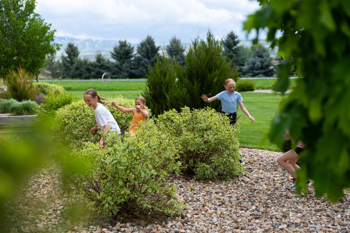 Happy Kids Playing in River Rock Bed Shrubs 6