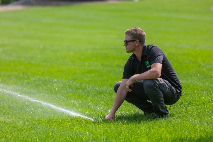 lawn care tech adjusting irrigation for green grass