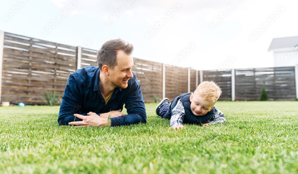 child and man lay on grass